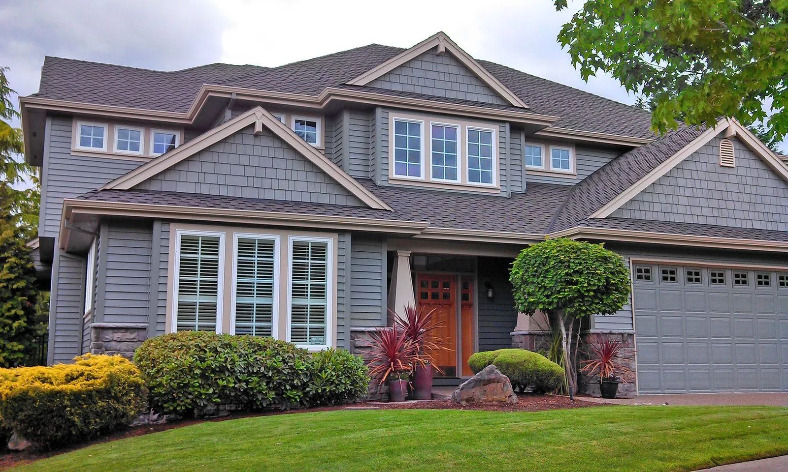 Grey craftsman house with shingled gables and tan trim after painting