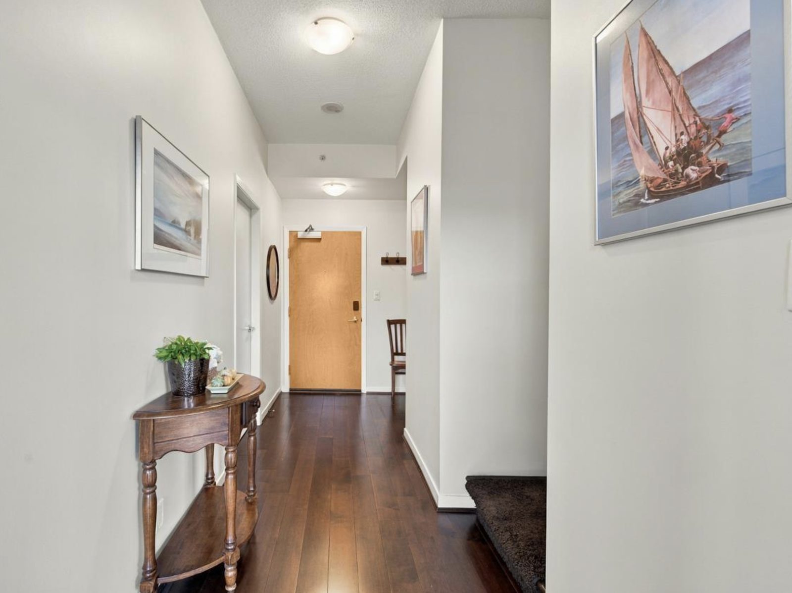 White hallway with dark hardwood floors and framed artwork