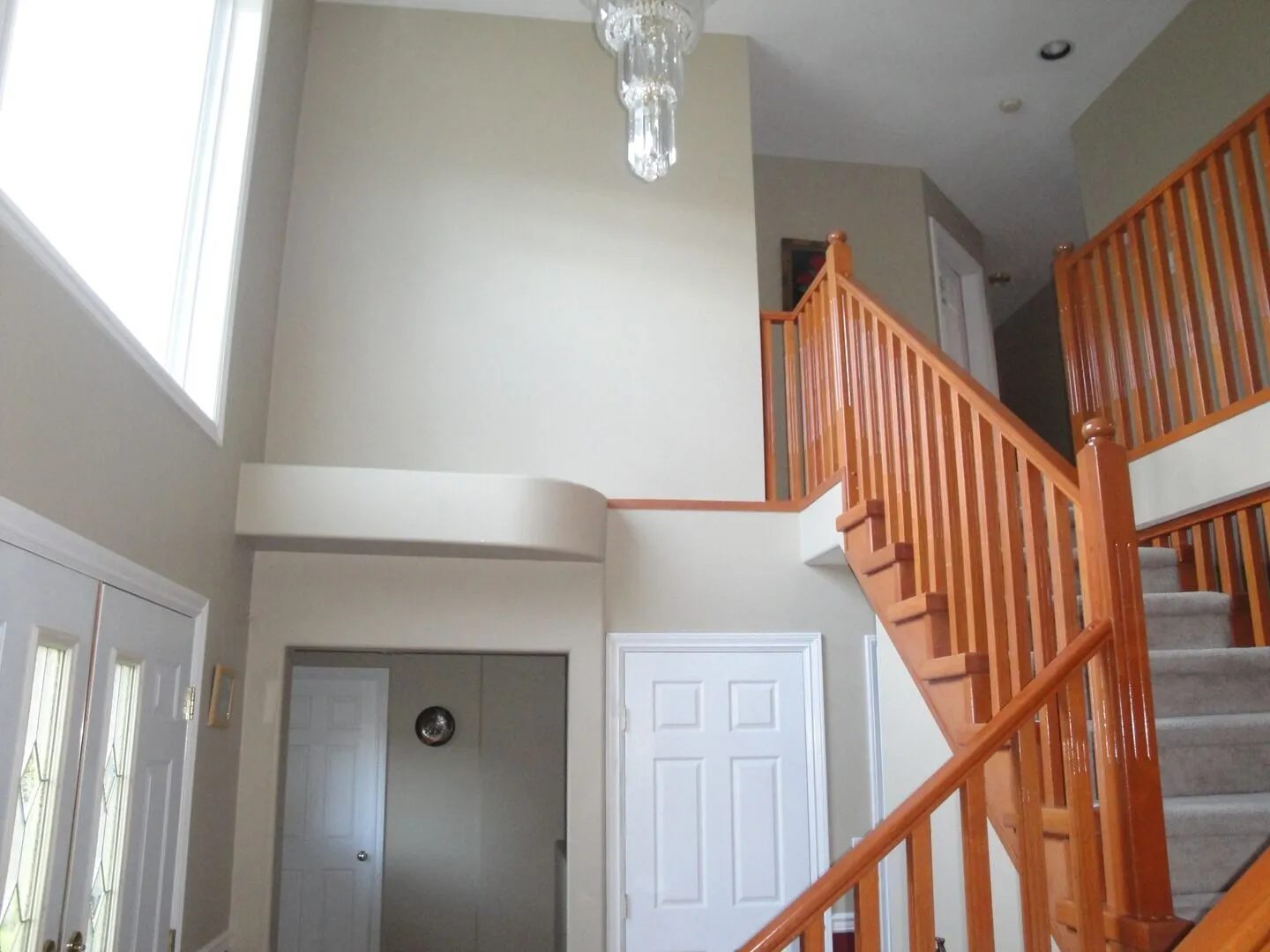 Two-storey foyer with oak railings, high ceiling and a chandelier
