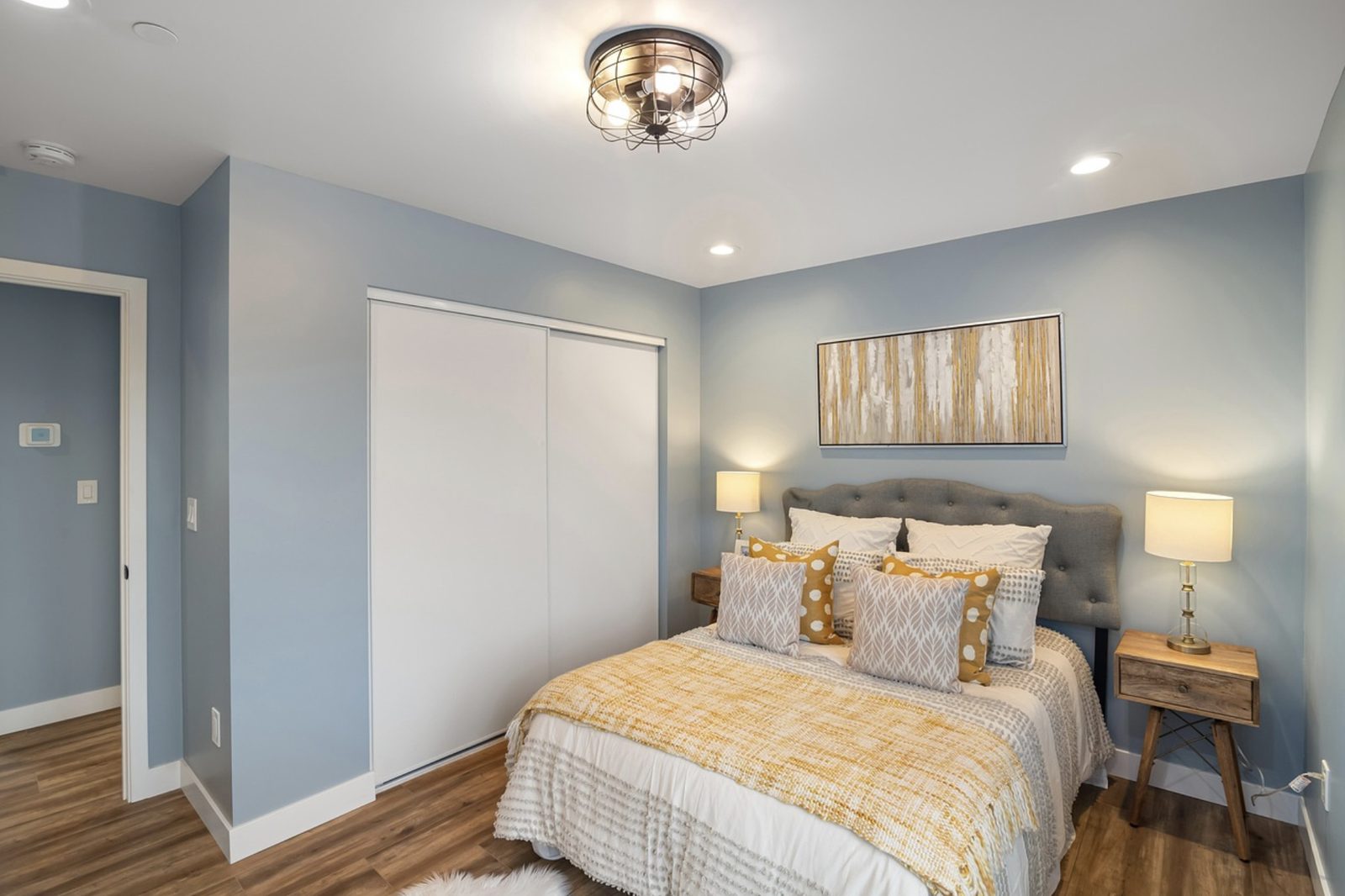 Bedroom with soft blue walls, white ceiling, trim and closet doors